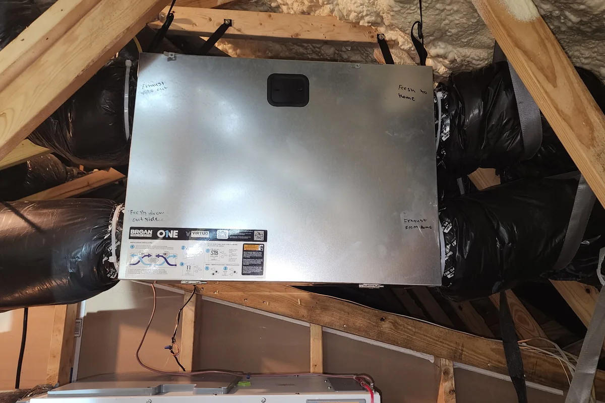 Broan ONE Virtuo ERV in a spray-foamed Triangle NC attic, its four insulated ducts hand-labeled fresh from outside, fresh to home, exhaust from home, and exhaust to out