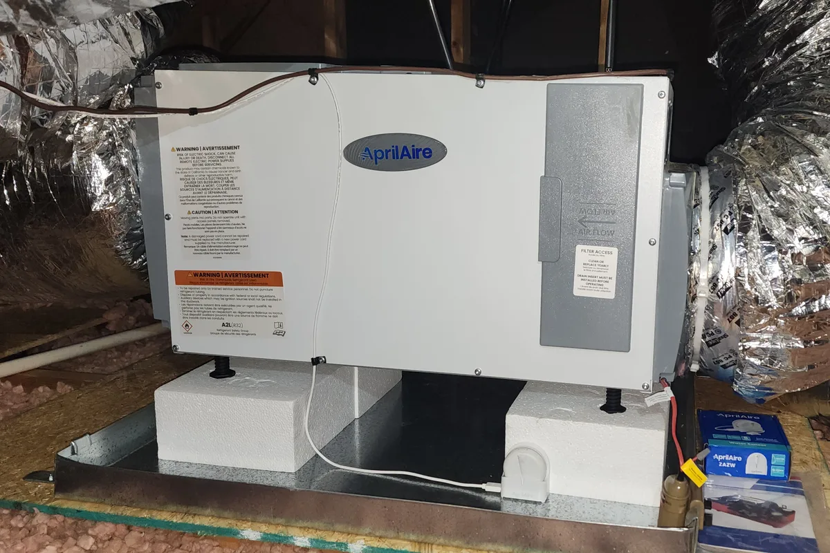 AprilAire whole-house dehumidifier installed and connected to ductwork in a Wake County NC attic