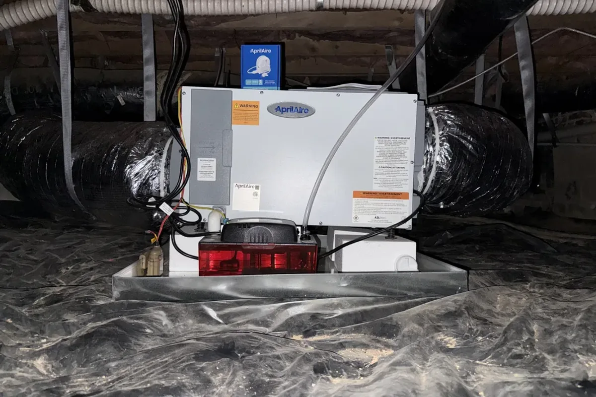AprilAire dehumidifier installed on a stand above the vapor barrier in a Wake County NC crawl space