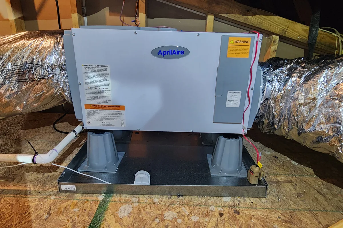 AprilAire whole-house dehumidifier connected to HVAC ductwork in a Wake County NC attic
